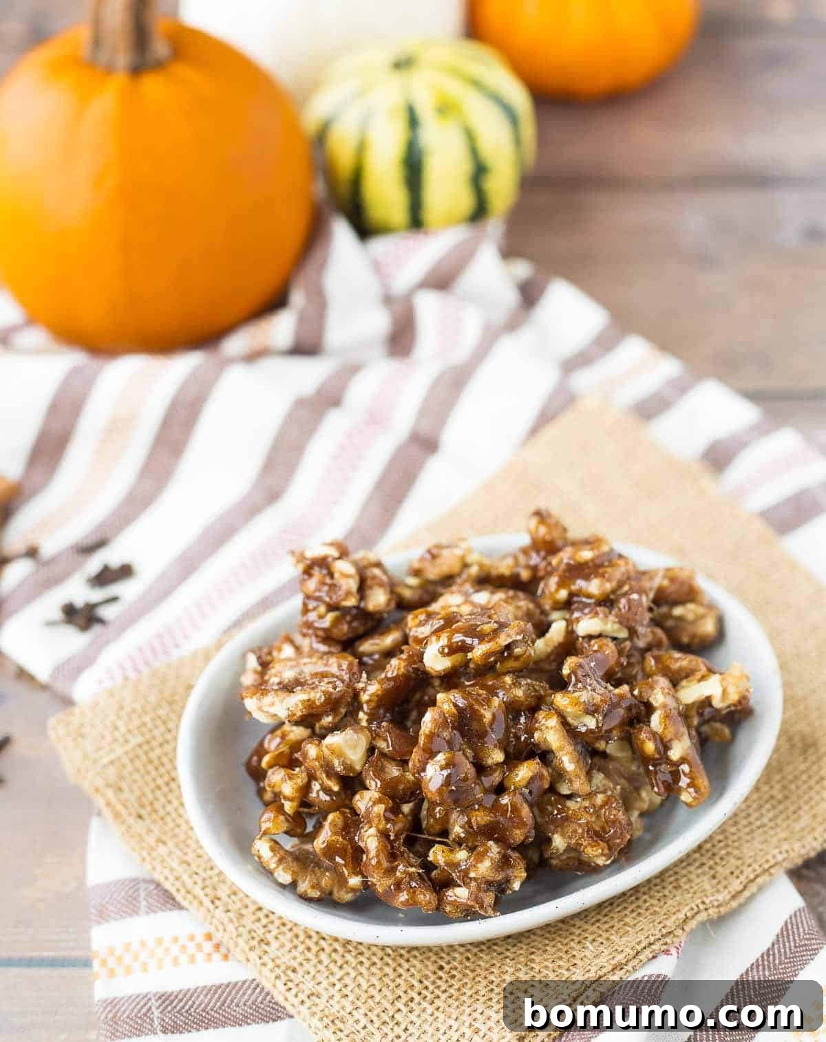 A rustic bowl filled with pumpkin spice candied walnuts, positioned on a wooden table with soft focus pumpkins creating a warm, inviting autumn backdrop.
