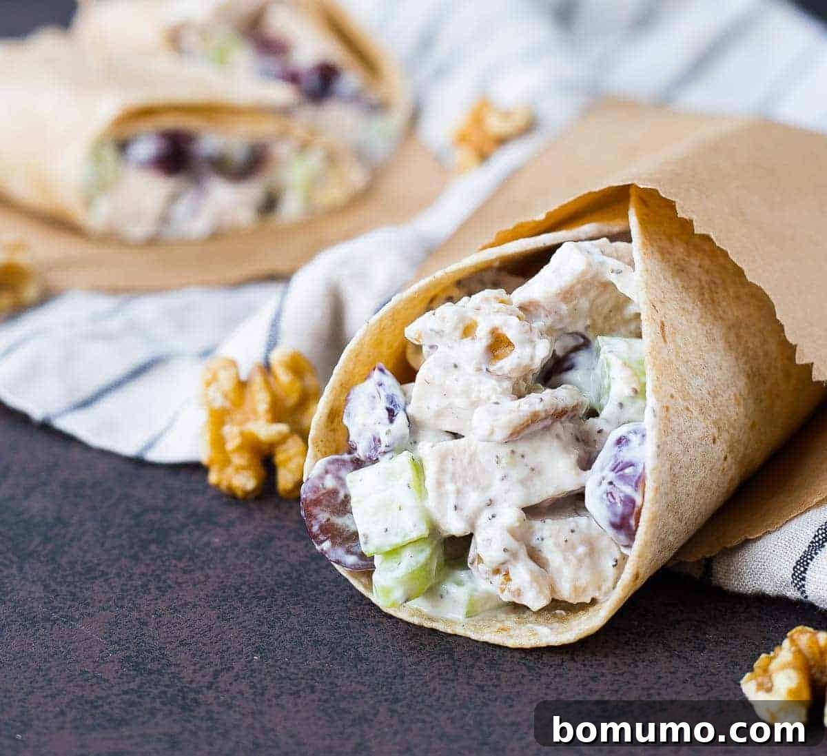 Close up of chicken salad wrap with walnuts scattered on the table.