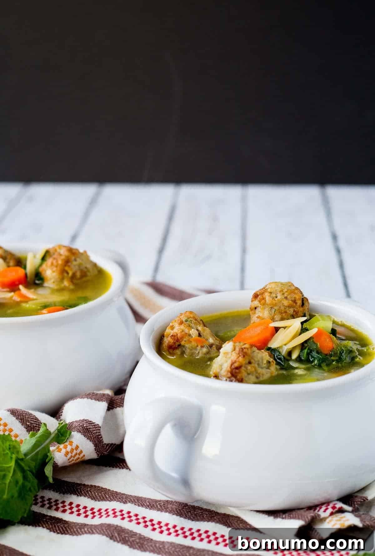 Three bowls of healthy meatball orzo soup, garnished with fresh herbs and ready to serve, showcasing the vibrant ingredients.