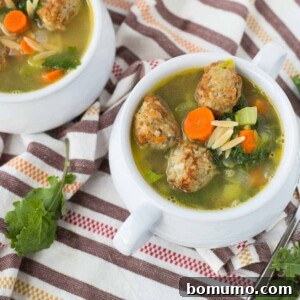 Overhead of healthy meatball orzo soup served in white bowls, garnished with fresh herbs.