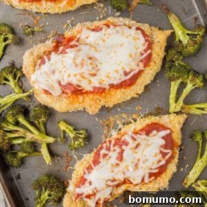 Overhead view of a cooked sheet pan chicken Parmesan with golden chicken and perfectly roasted broccoli.