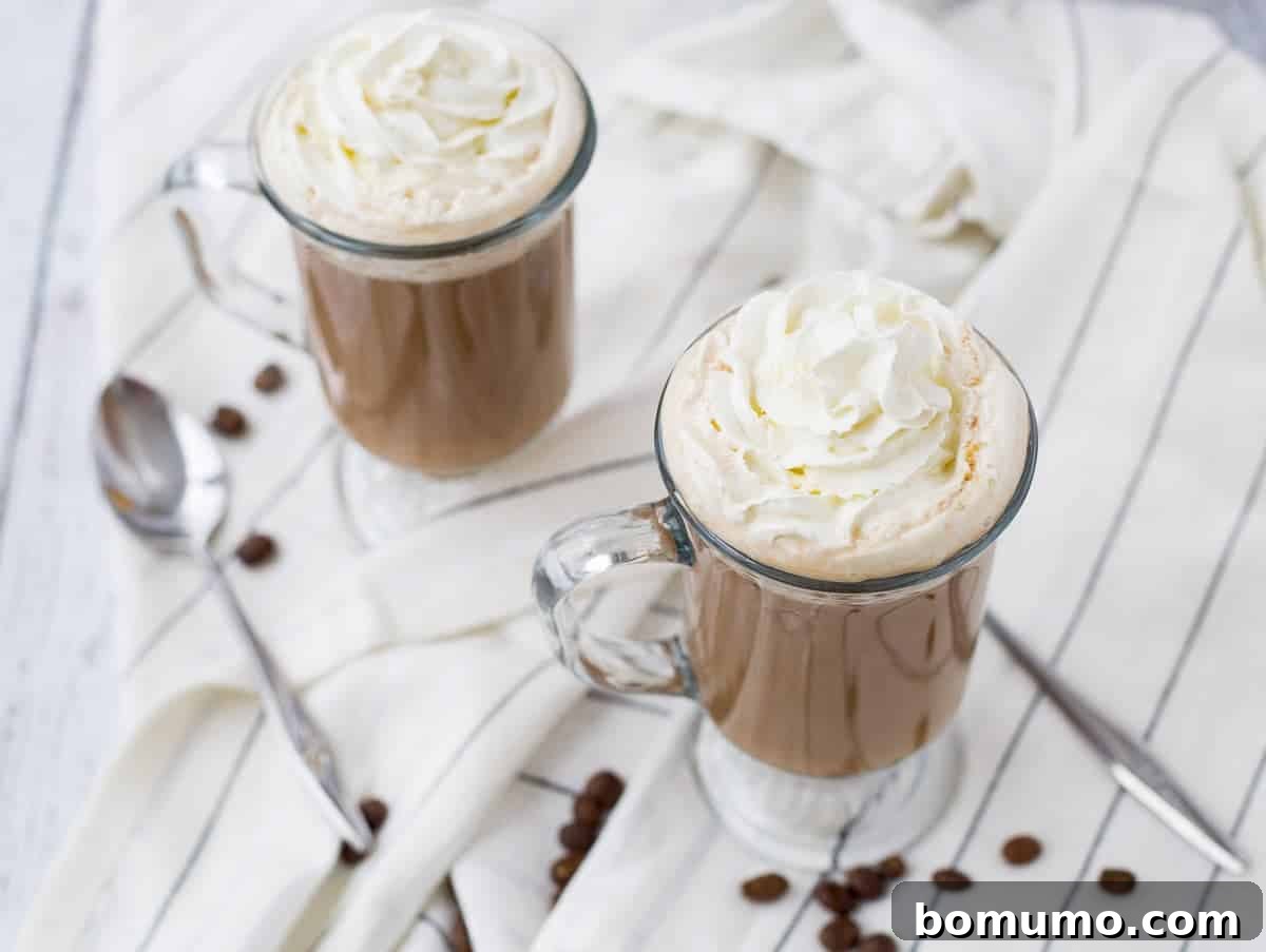 Overhead of two mugs of white russian on white striped cloth.