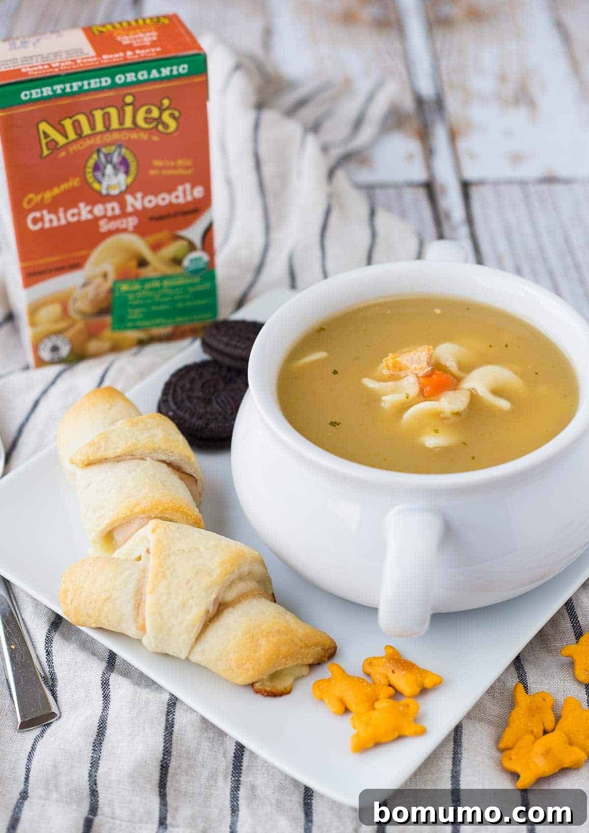 Crescent roll sandwiches on square plate with bowl of soup, bunny crackers, and oreo cookies.