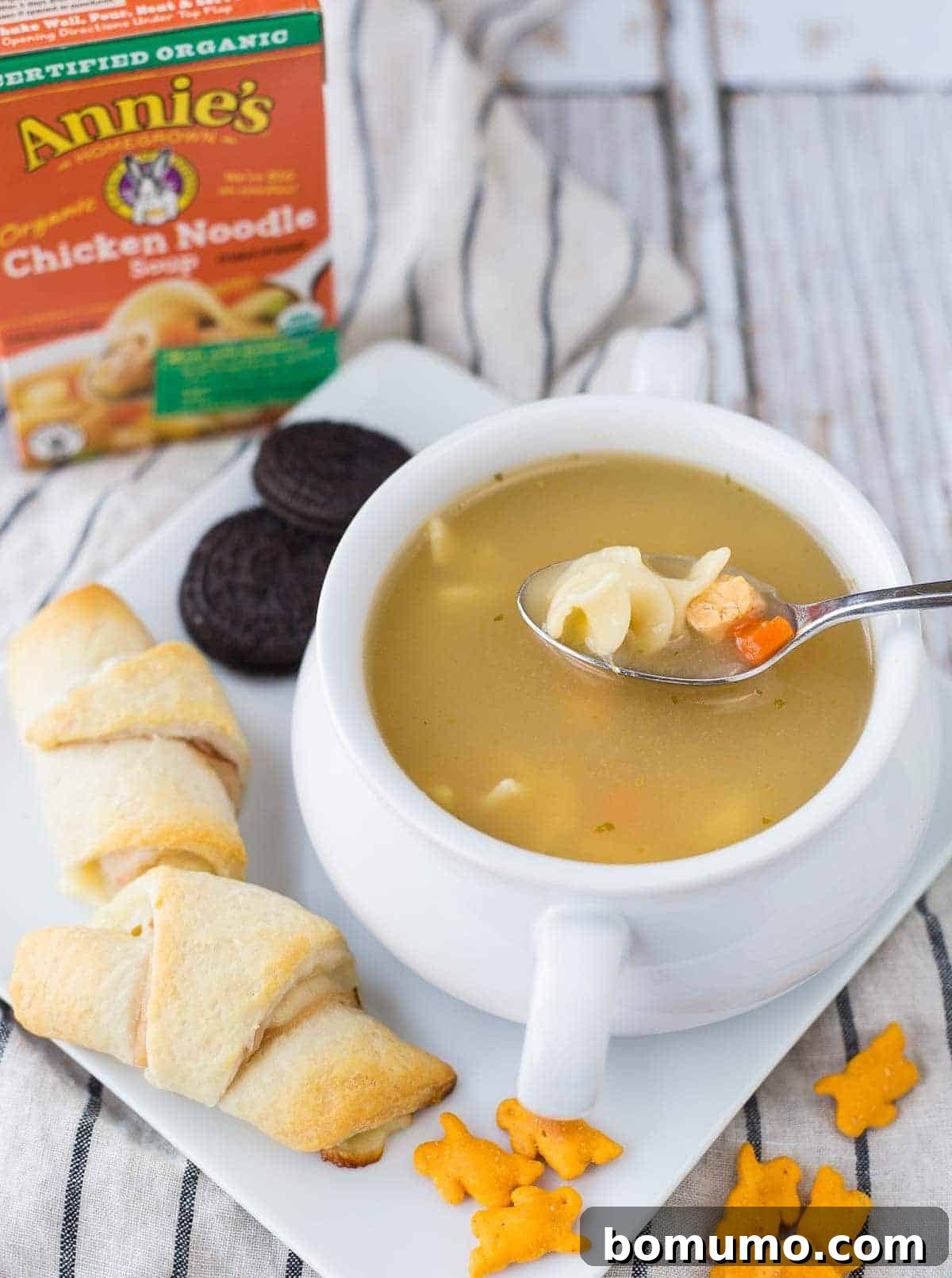 Sandwiches on plate with soup. Box of Annie's Chicken Noodle soup mix in background.