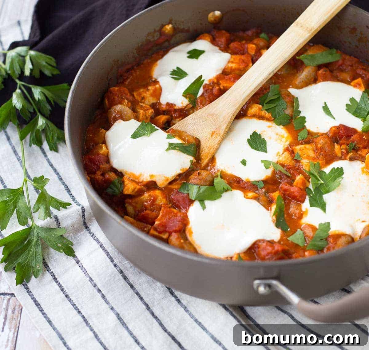Skillet with wooden spoon inserted into gnocchi dish.