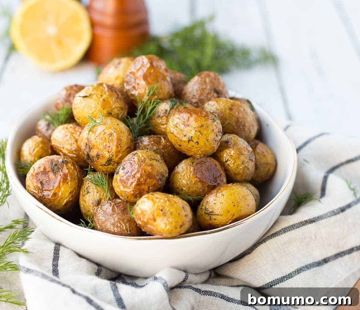 Crispy roasted potatoes arranged on a striped cloth, with fresh dill, lemon wedges, and a pepper grinder in the background, highlighting the fresh ingredients.