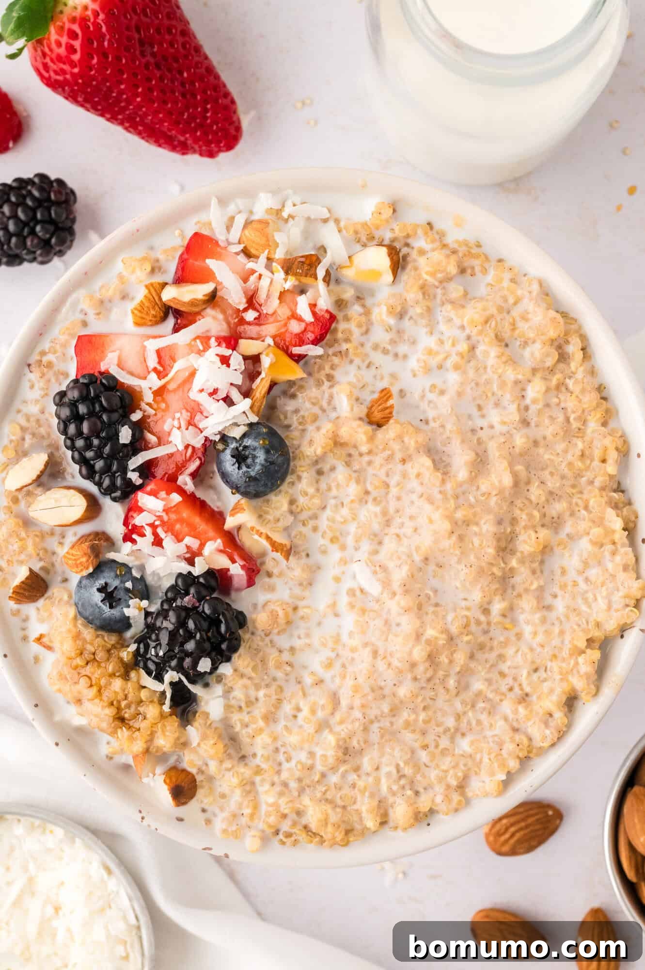 A vibrant bowl of breakfast quinoa, generously topped with an assortment of fresh berries and delicate coconut flakes, ready to be enjoyed.