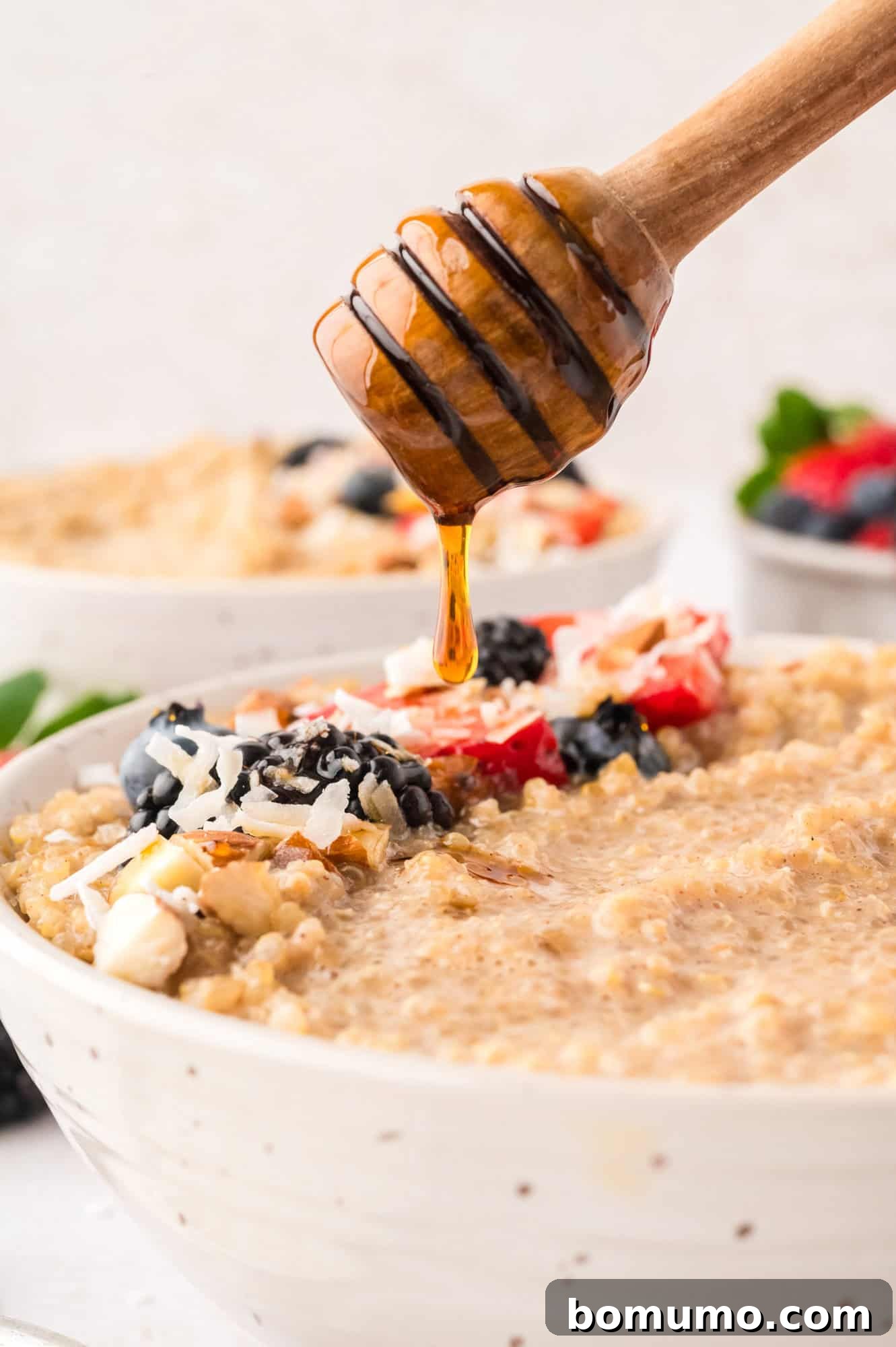 Golden honey being delicately drizzled over a bowl of warm, creamy breakfast quinoa, adding a touch of natural sweetness.