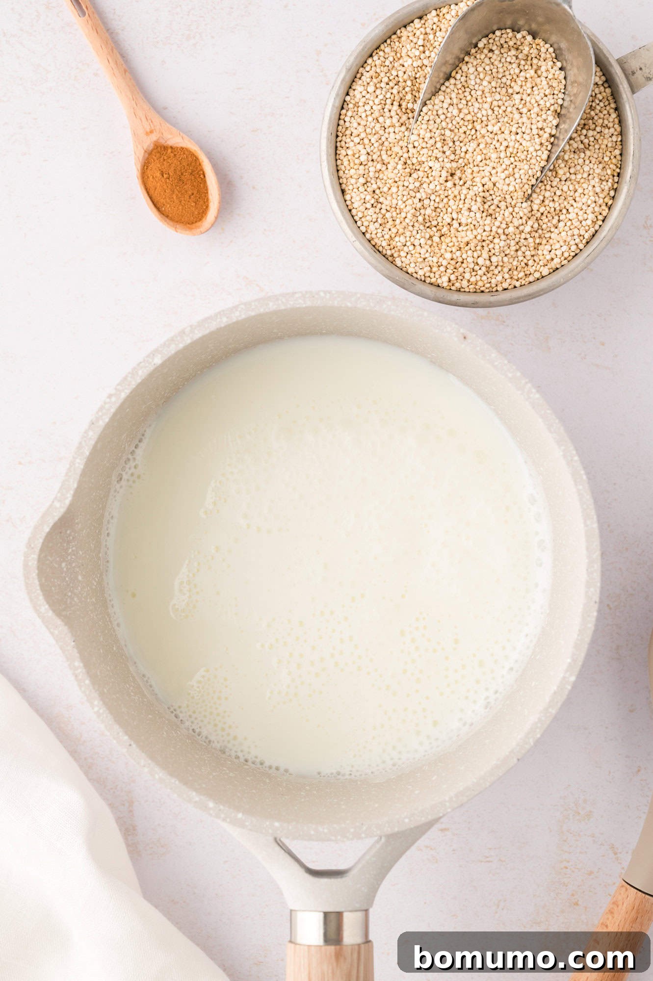 Milk and water simmering in a saucepan on the stovetop, forming the base for the breakfast quinoa.