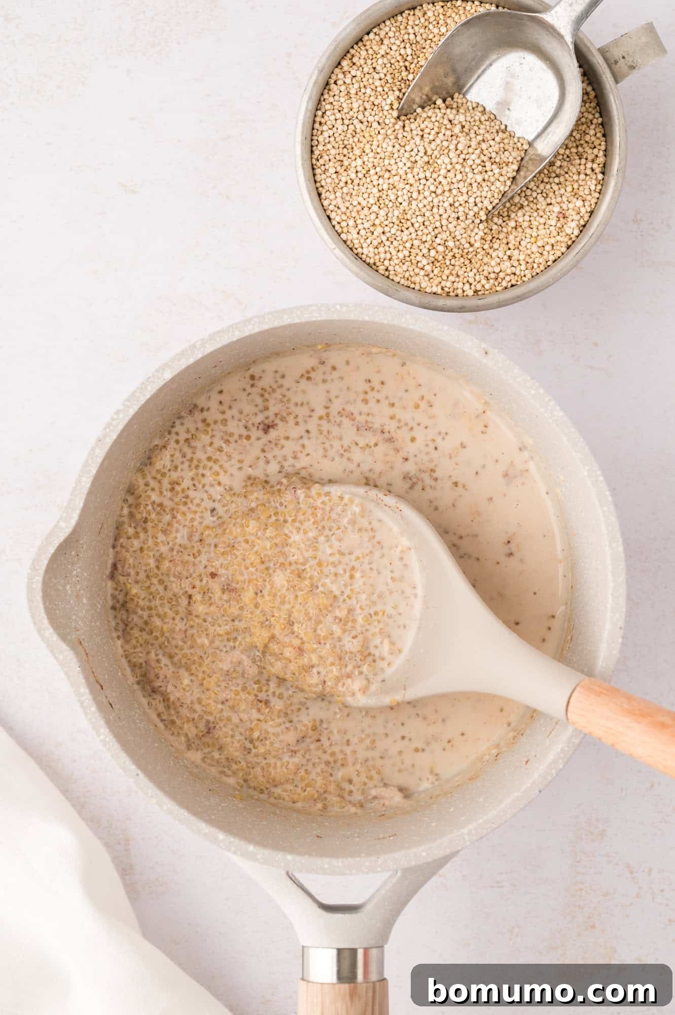 A spoonful of cooked quinoa, illustrating its fluffy texture and visible 'tails' before the final resting period.