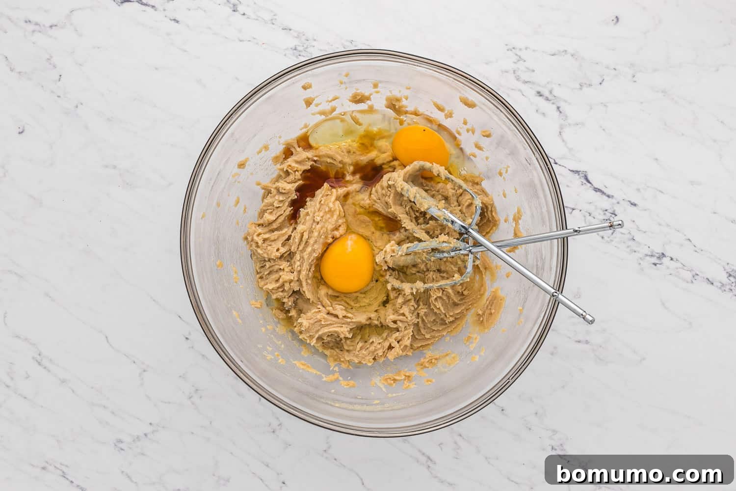 Eggs being added to the creamed butter and sugar mixture in a bowl.