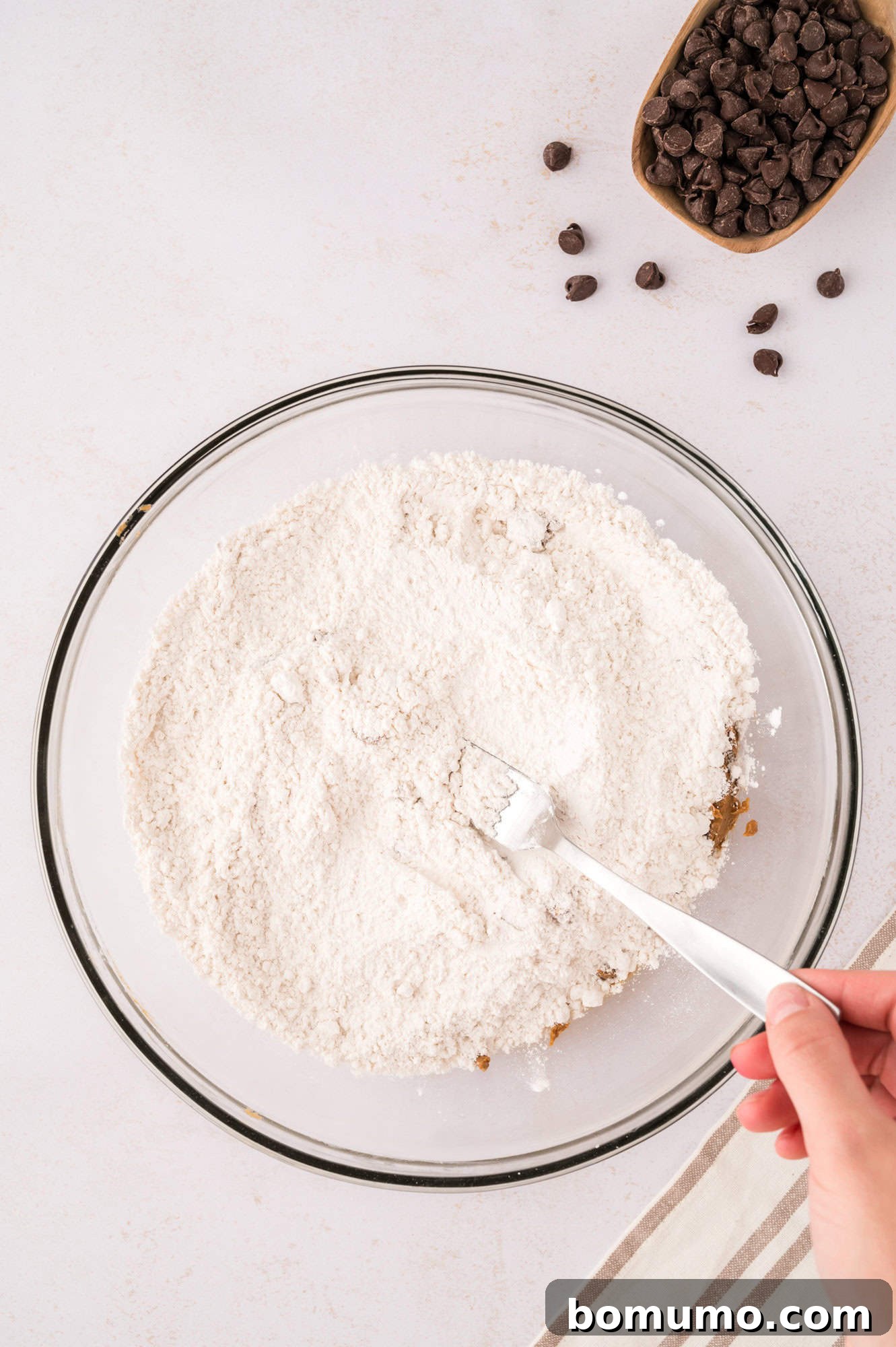Dry ingredients being gently mixed on top of the wet ingredients in a bowl, a clever step to avoid using an extra bowl.