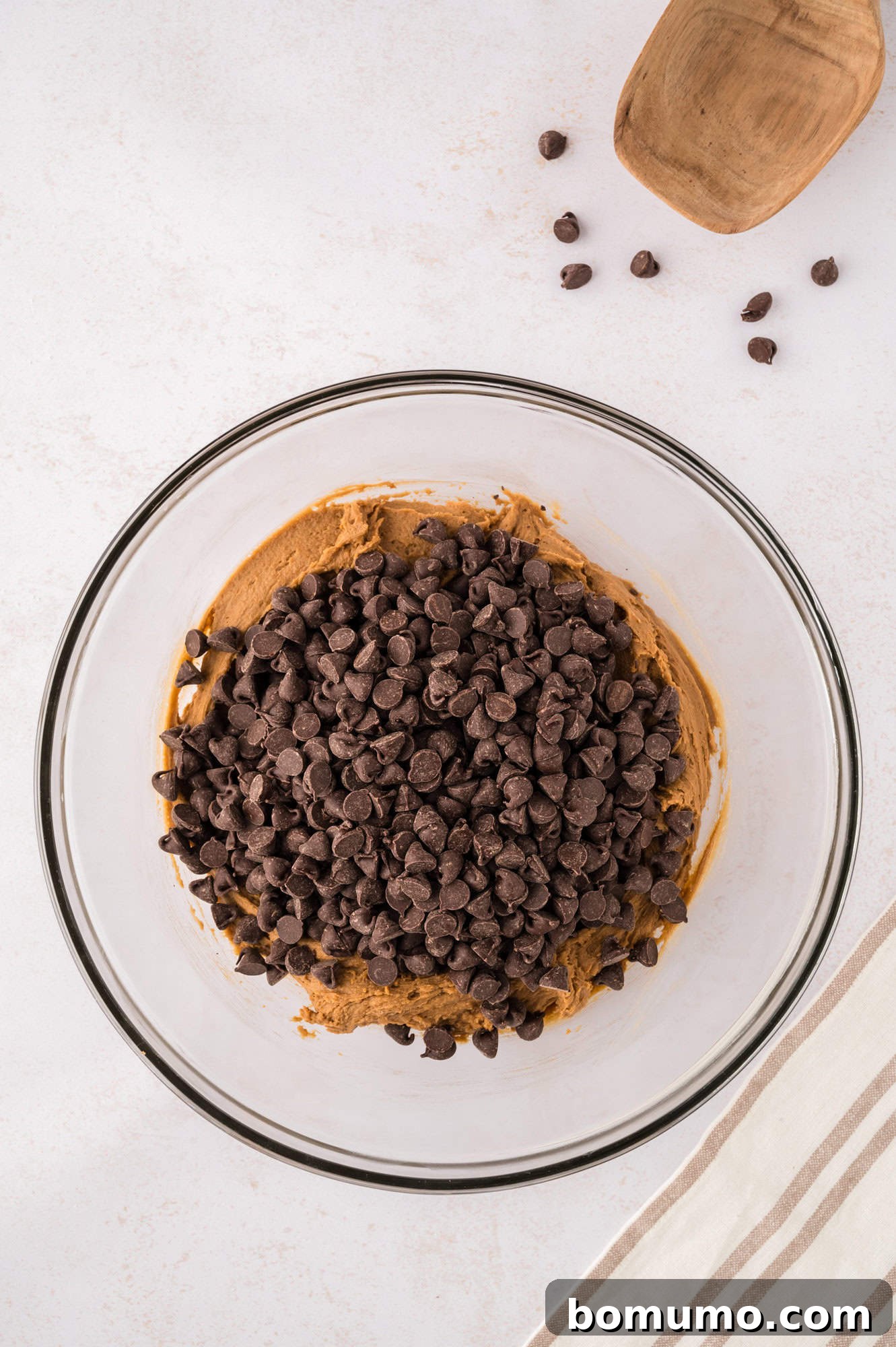 Chocolate chips generously added to the cookie dough, awaiting their final mix to be evenly distributed.