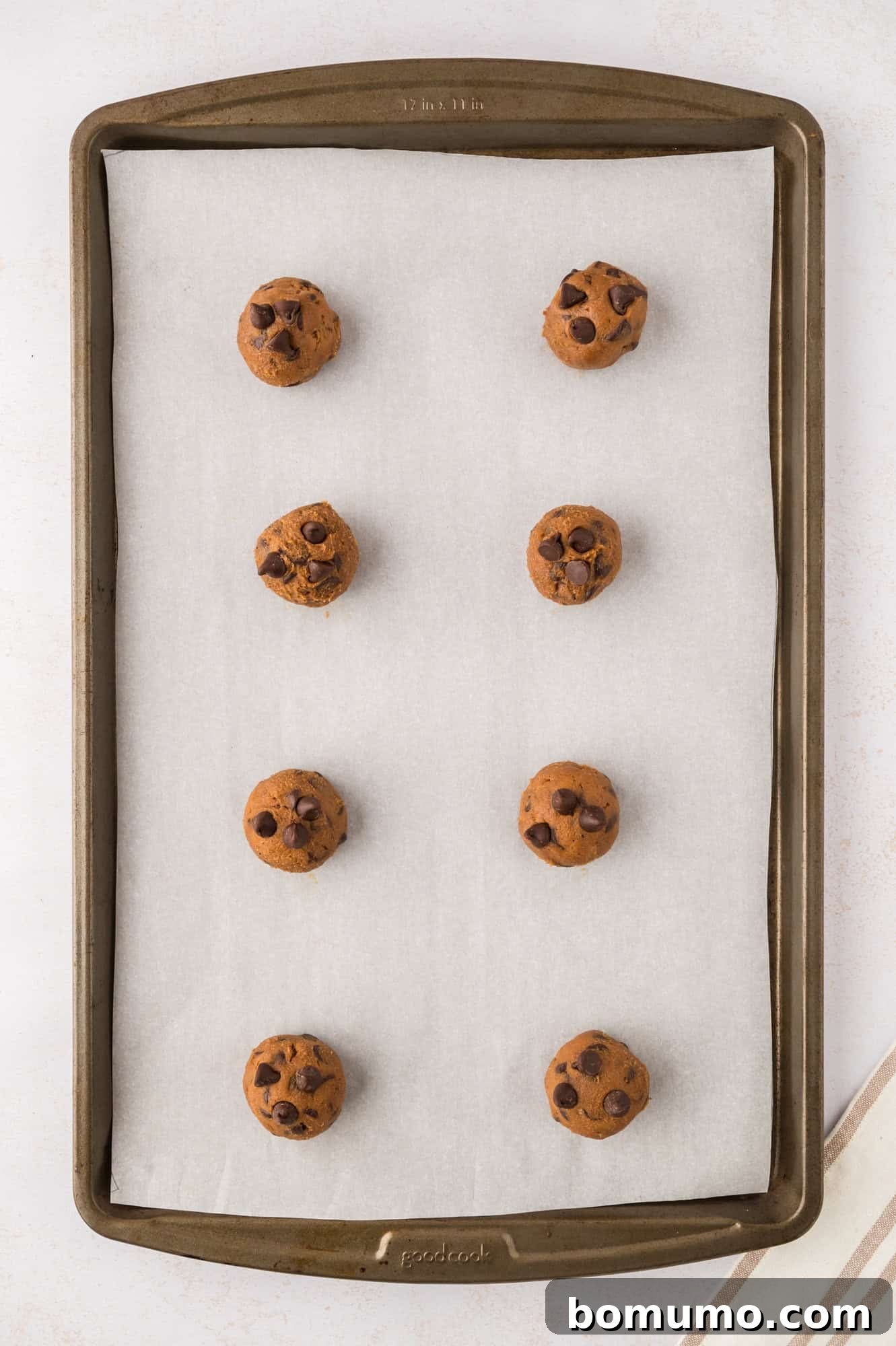 Rows of unbaked coffee cookie dough balls meticulously arranged on a cookie sheet, ready for the oven.