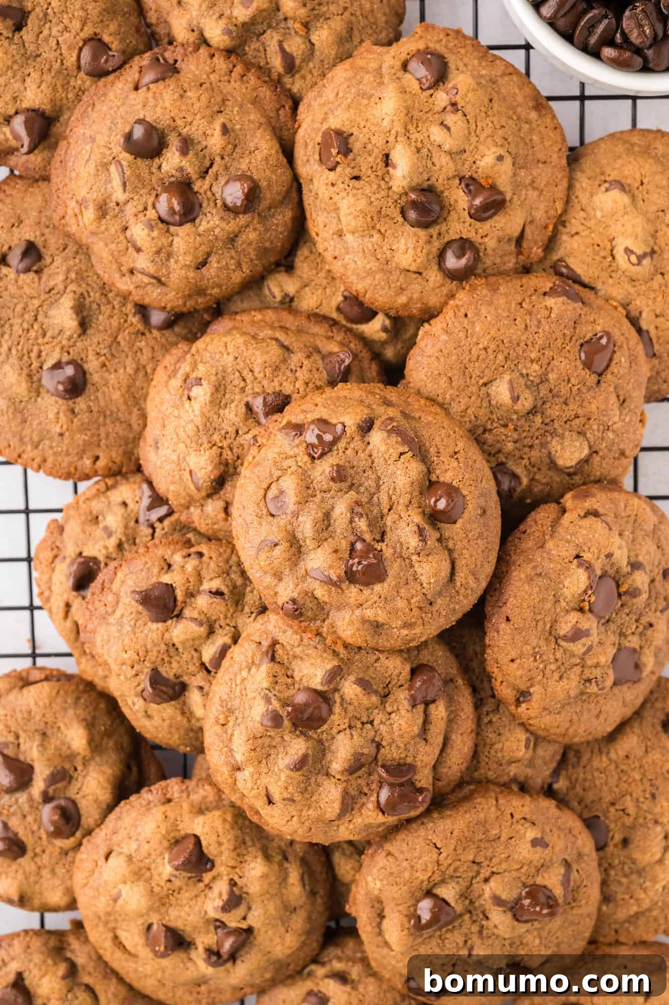 A neat stack of golden-brown coffee cookies with chocolate chips, cooling on a wire rack.