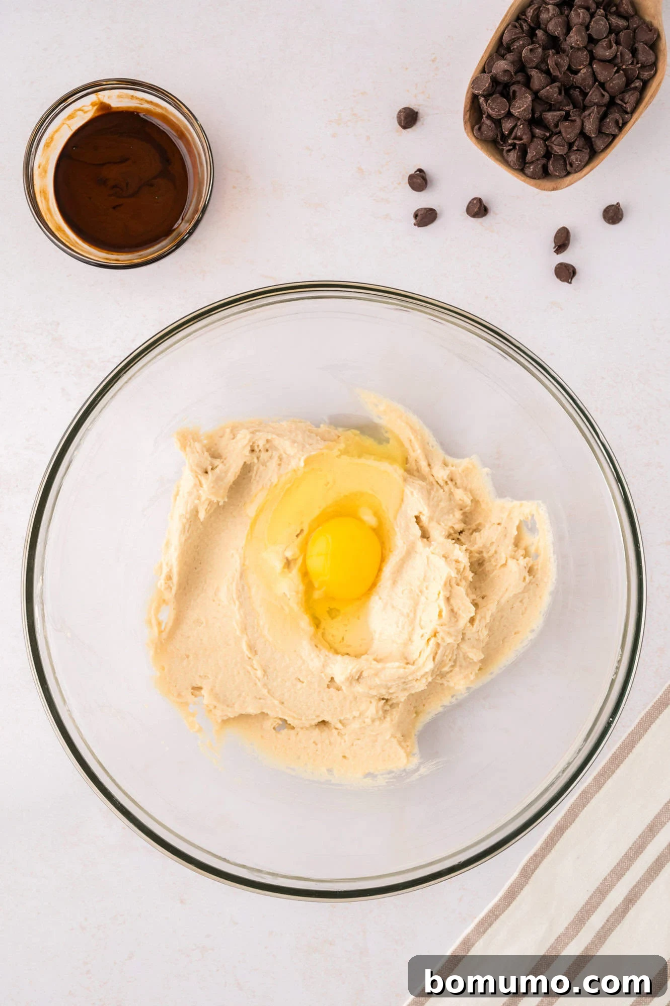 A single large egg carefully cracked into the creamed butter and sugar mixture, ready to be beaten.