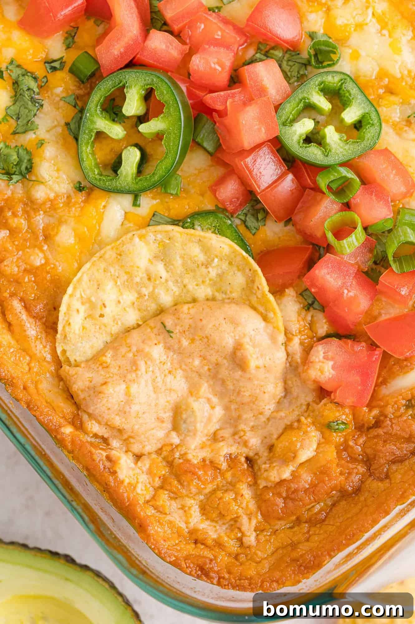 Smooth Bean Party Pleaser 3 Chip being dipped into warm, creamy refried bean dip, showcasing its perfect texture.