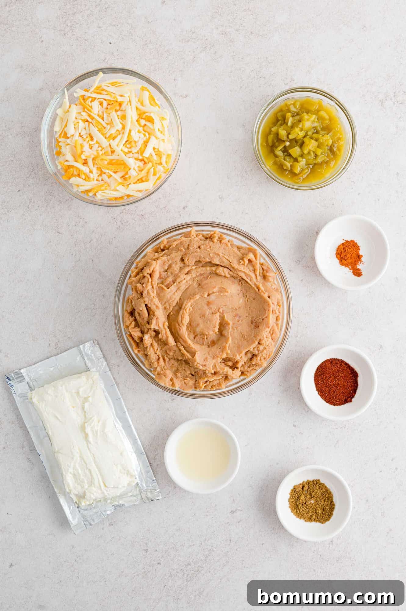 Smooth Bean Party Pleaser 4 Ingredients needed for the refried bean dip recipe, including refried beans and cream cheese, laid out on a counter.