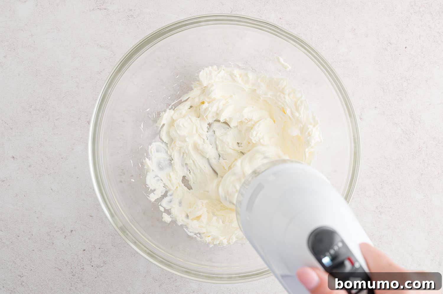 Smooth Bean Party Pleaser 5 Cream cheese being whipped with an electric mixer in a mixing bowl.