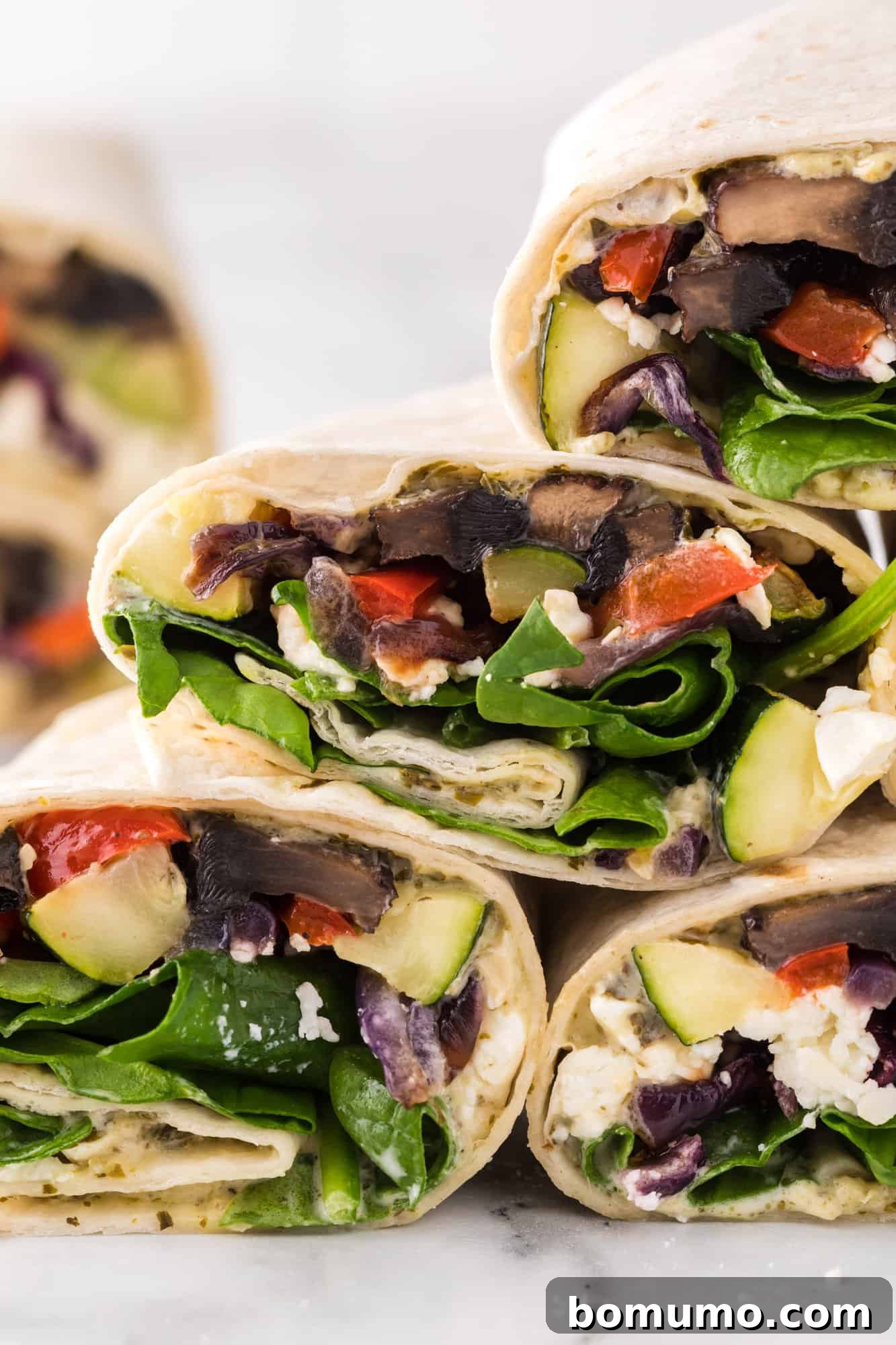 A neatly stacked collection of fresh roasted vegetable wraps, showcasing their perfectly rolled forms.