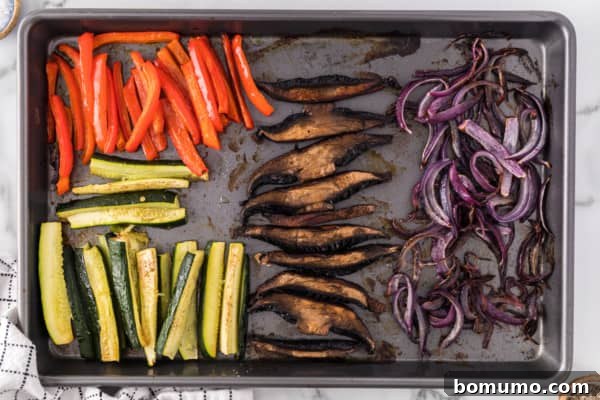 Freshly roasted vegetables, golden brown and tender, spread across a sheet pan, having just come out of the oven.