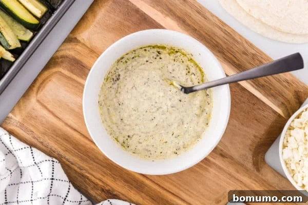 Creamy pesto mayo, perfectly mixed, in a white bowl with a spoon, ready for spreading, on a rustic wooden cutting board.