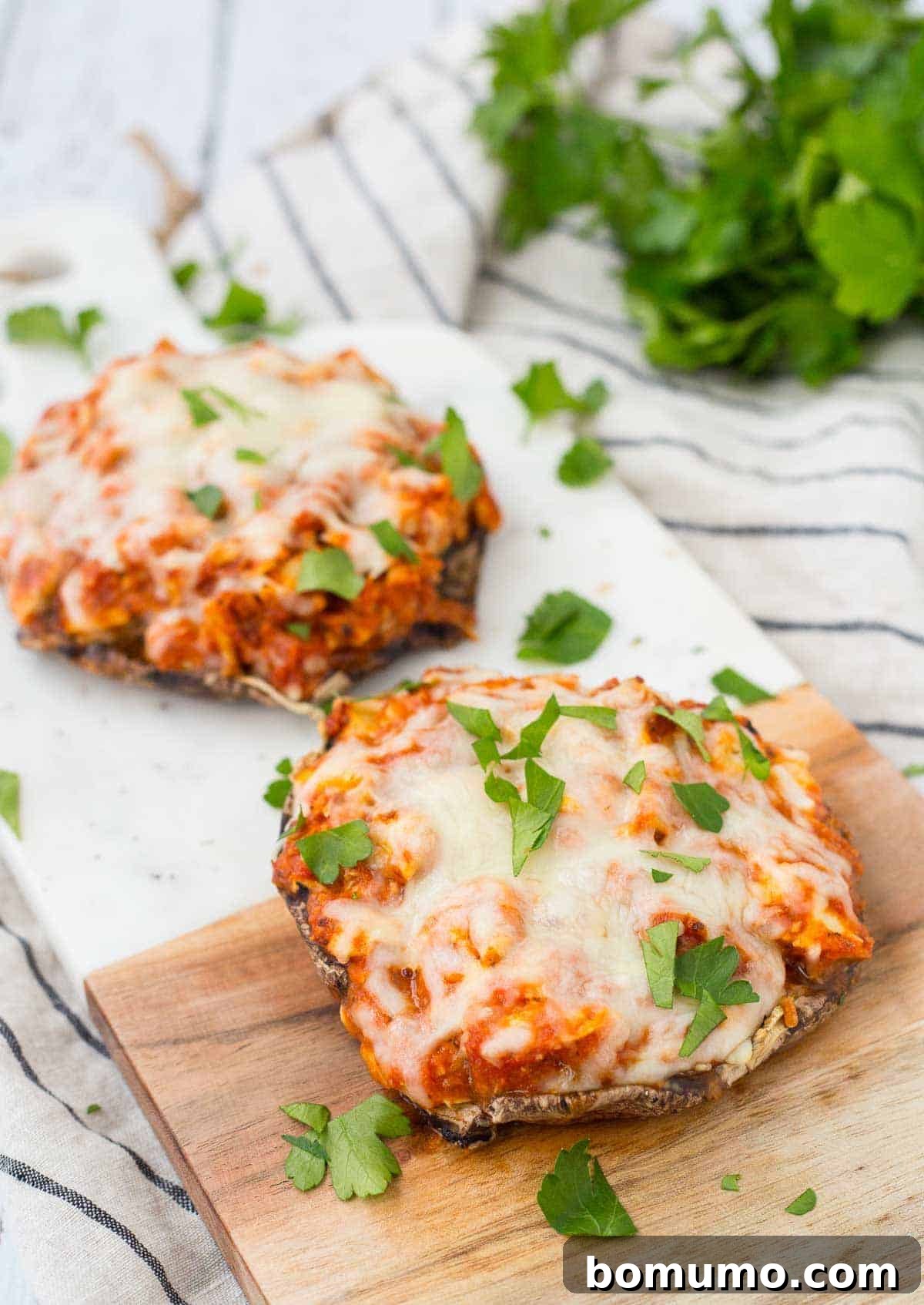 Two servings of chicken Parmesan on a cutting board, garnished with chopped parsley. A healthy and delicious weeknight meal.