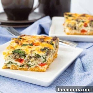 A perfectly portioned square of a golden-brown egg white casserole with a sweet potato crust, ready to be served on a white plate. The image emphasizes the appetizing texture and vibrant colors of this healthy breakfast option.