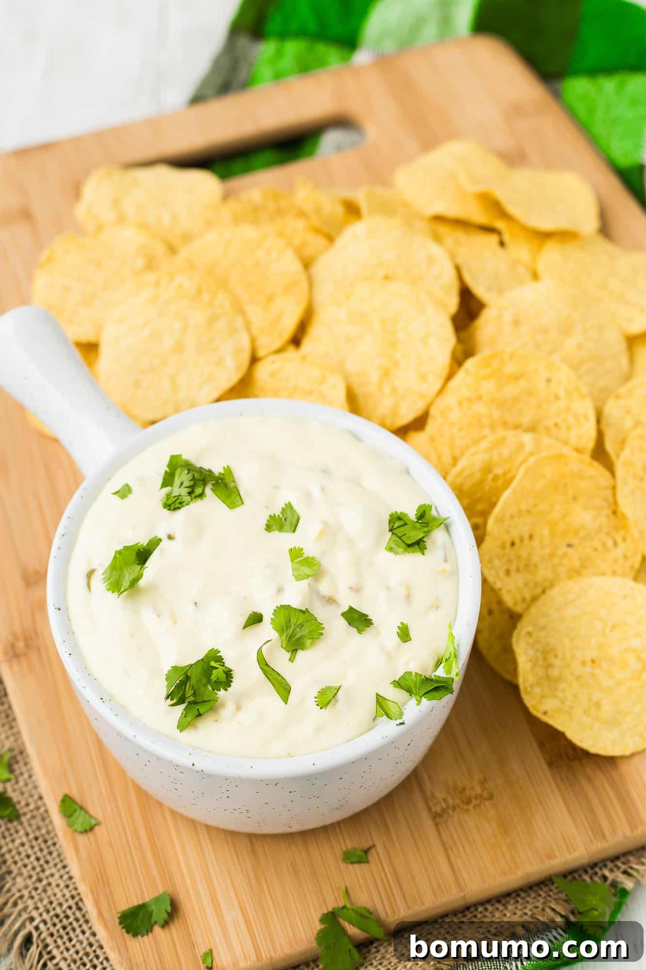Crockpot queso blanco in a small white bowl, surrounded by chips.