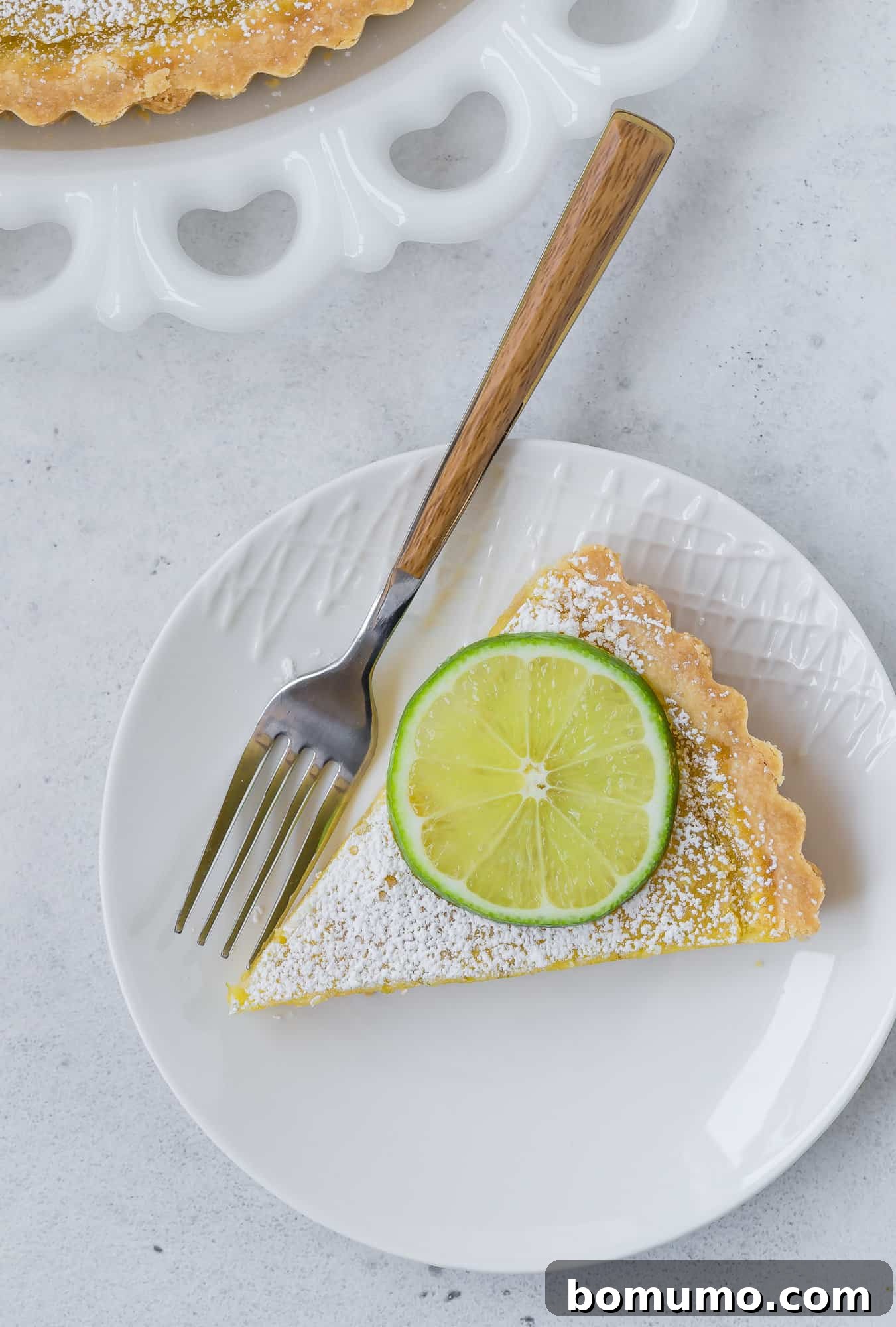 Close-up overhead view of a slice of lemon lime tart, highlighting the smooth, pale yellow filling and crumbly shortbread crust.