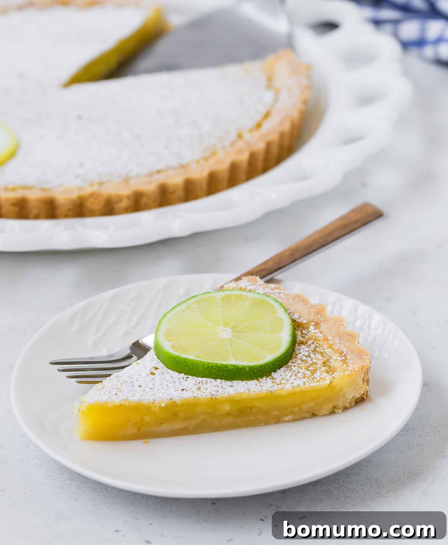 A beautifully garnished slice of lemon lime tart, topped with a thin slice of fresh lime, ready to be served.