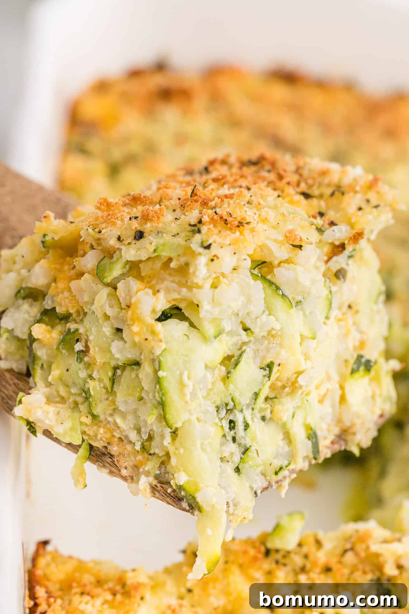 A close-up view of the zucchini rice casserole, highlighting its rich, cheesy texture and golden-brown crispy topping.