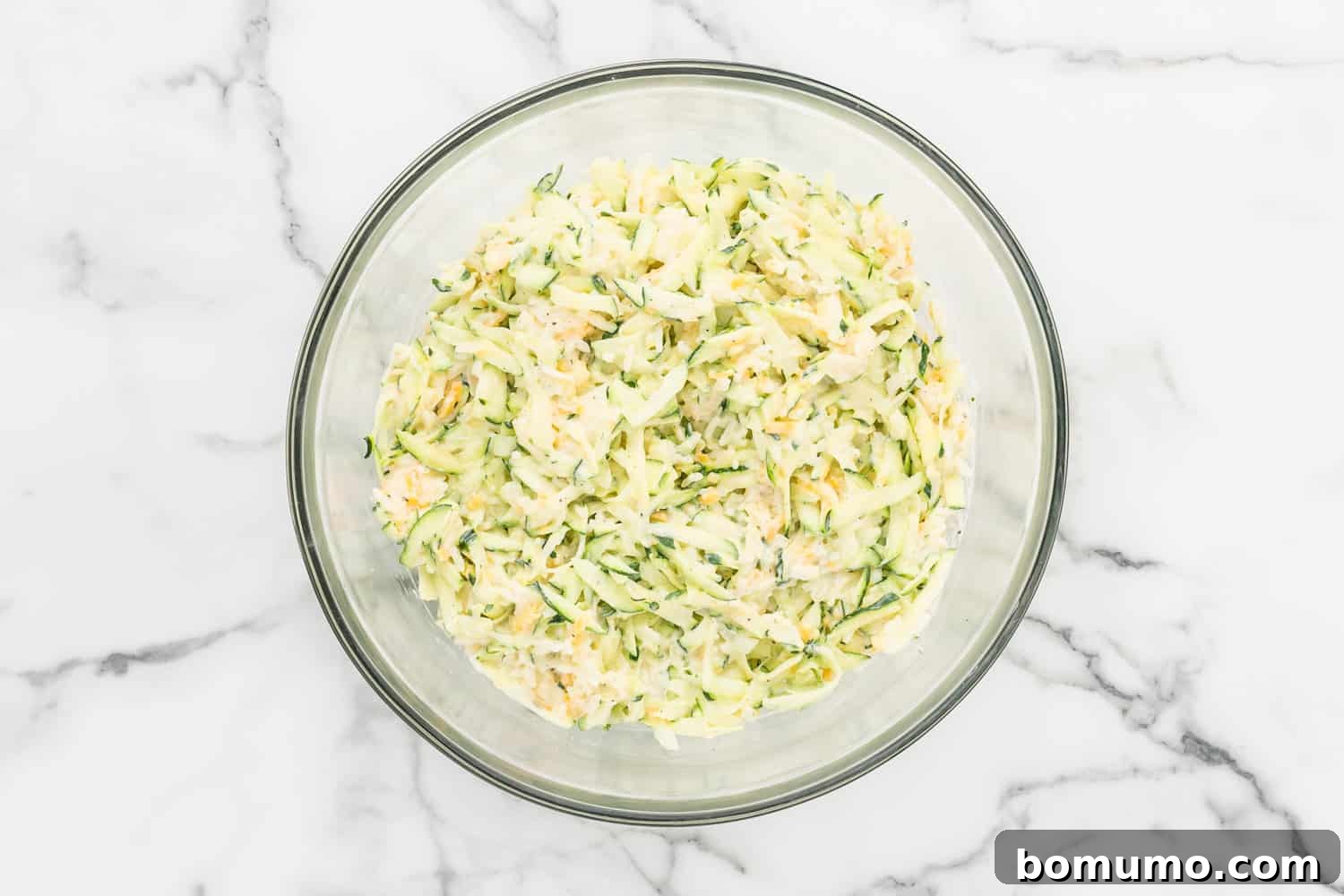 The fully combined zucchini, rice, and cheese mixture in a glass mixing bowl, showcasing its creamy and cohesive texture before baking.