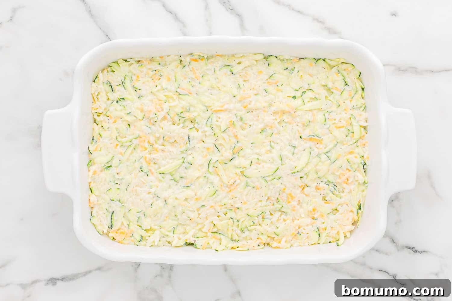 The zucchini and rice casserole mixture scraped into a baking dish, before the addition of the crispy panko topping.