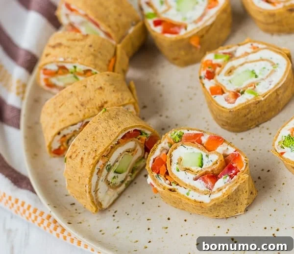 Creamy Veggie Pinwheels 4 Cream cheese rolls ups with fresh vegetables and herbs, beautifully sliced and presented on an earth-toned plate.