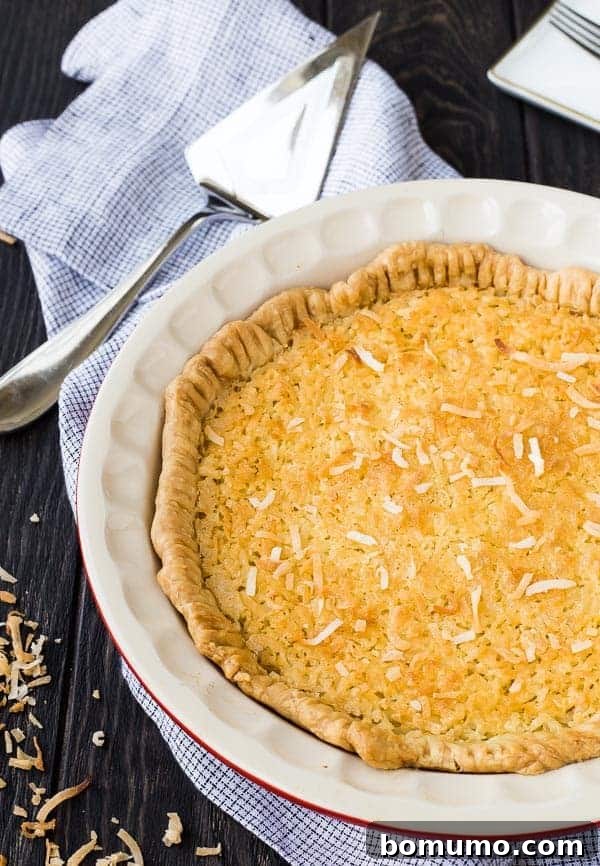 A whole, unsliced Coconut Custard Pie, golden brown and inviting, resting on a serving platter, ready to be enjoyed.