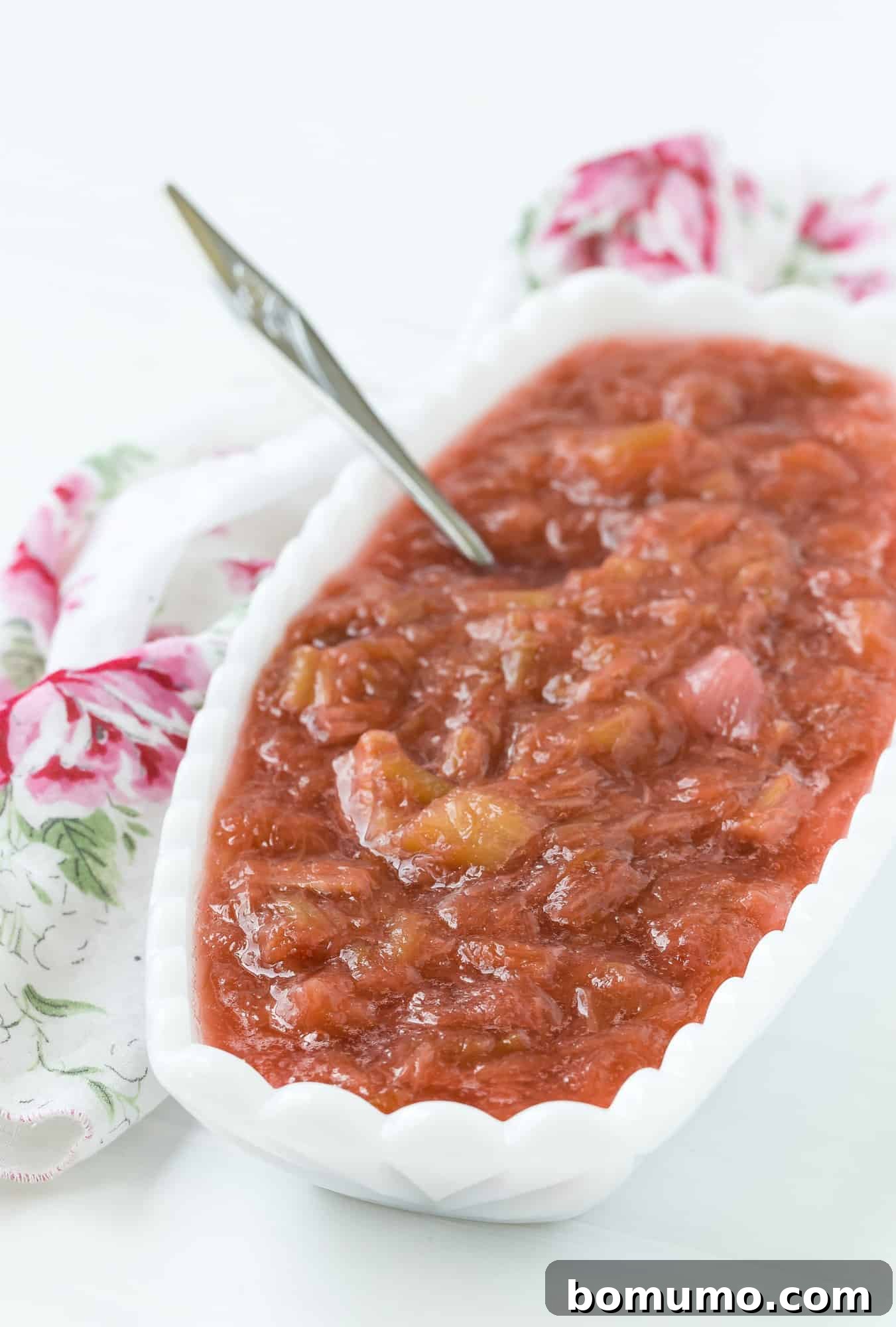 Vibrant homemade rhubarb sauce in a pristine white serving dish, perfectly capturing the essence of spring.