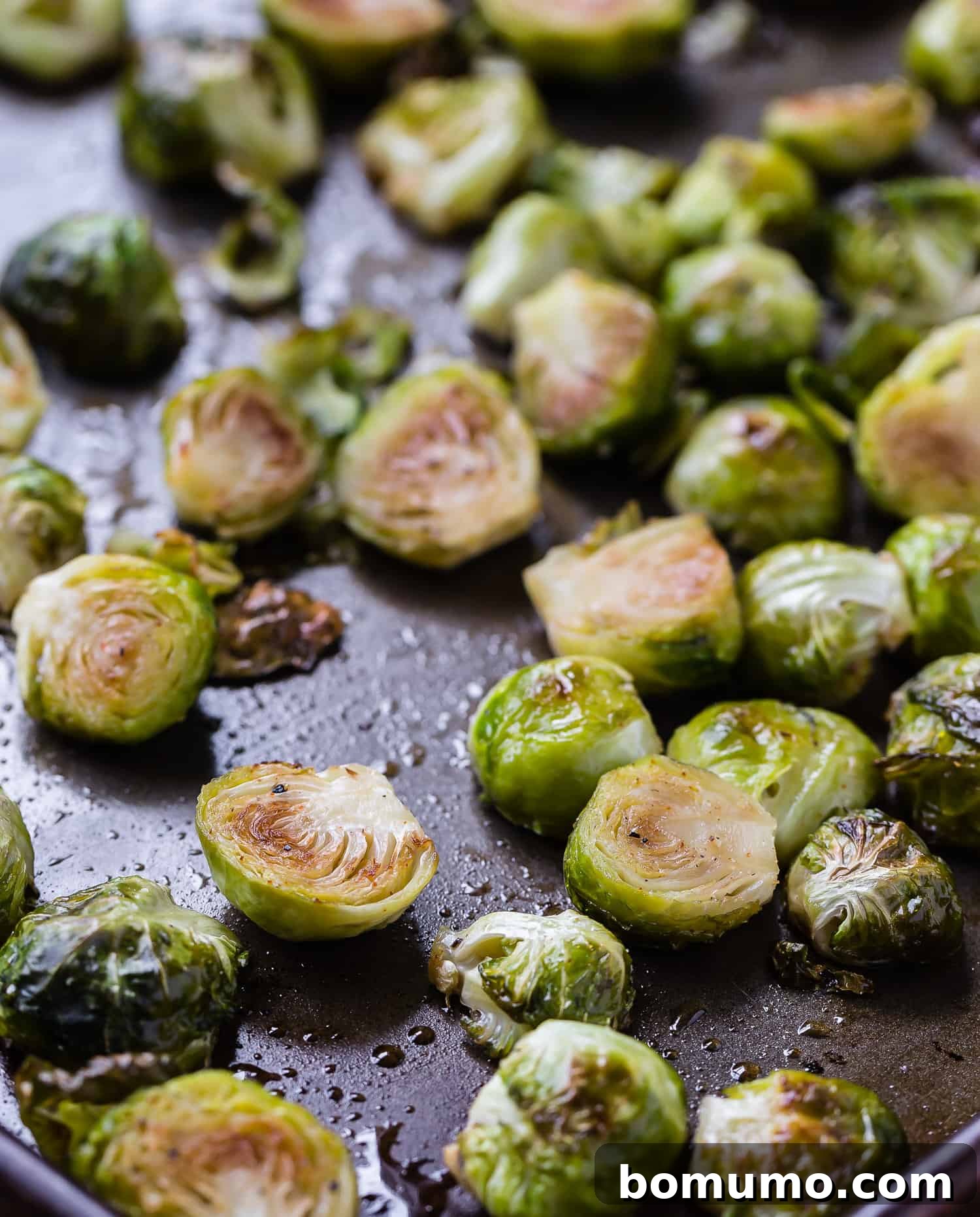 Perfectly cooked and glazed Brussels sprouts glistening on a sheet pan, ready to be served.
