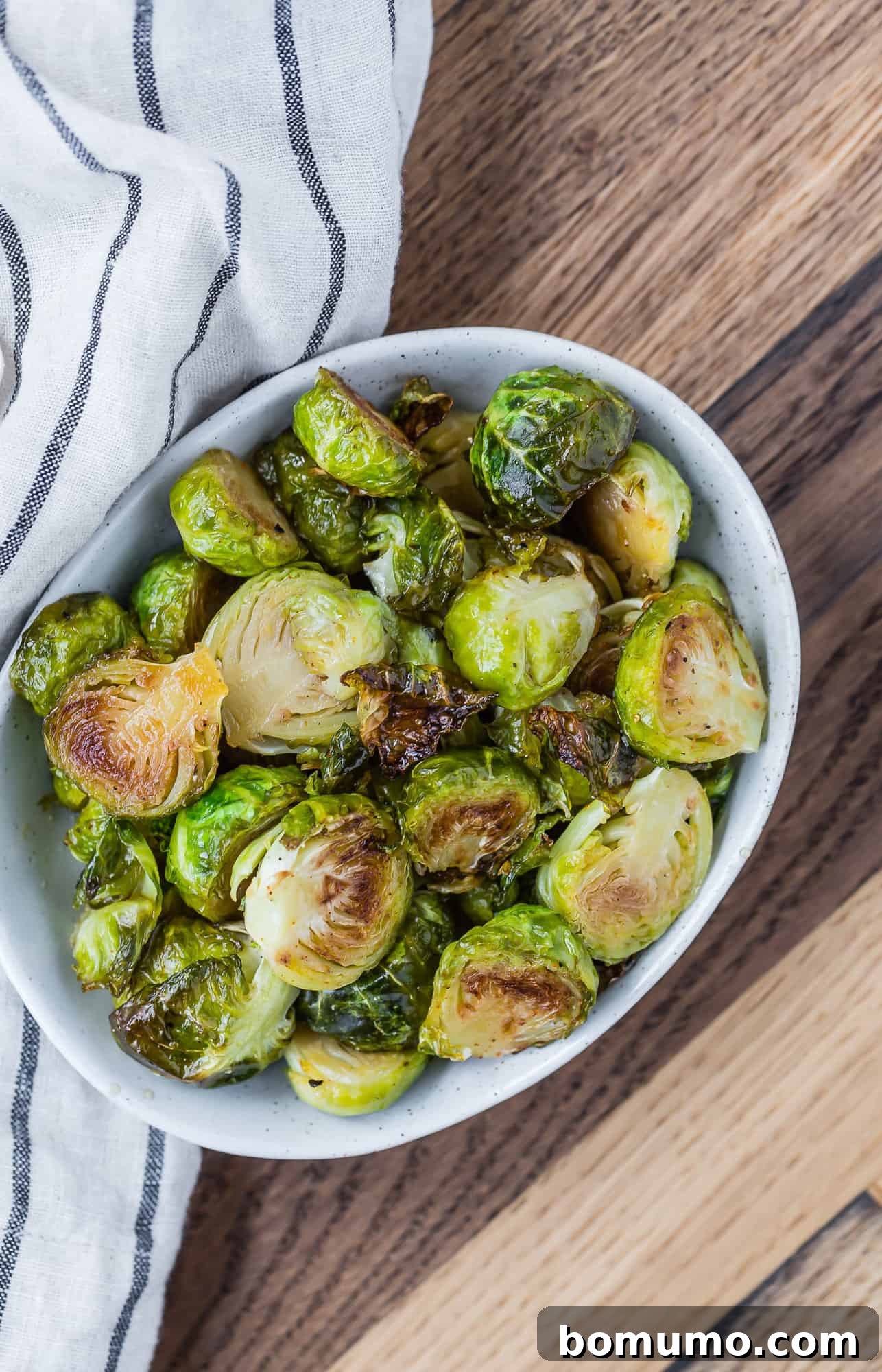 A bowl of roasted Brussels sprouts with a rustic wooden background, emphasizing their natural appeal.