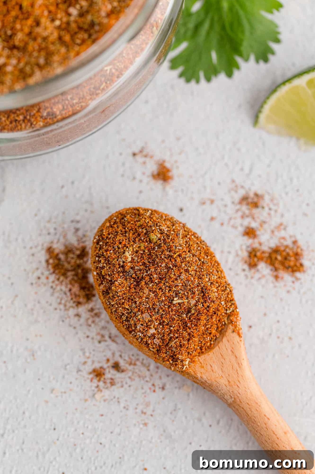 Taco seasoning on a small wooden spoon with some spilling off.