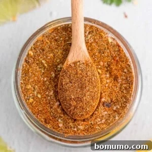 Overhead view of jar of taco seasoning with a wooden spoon in it.