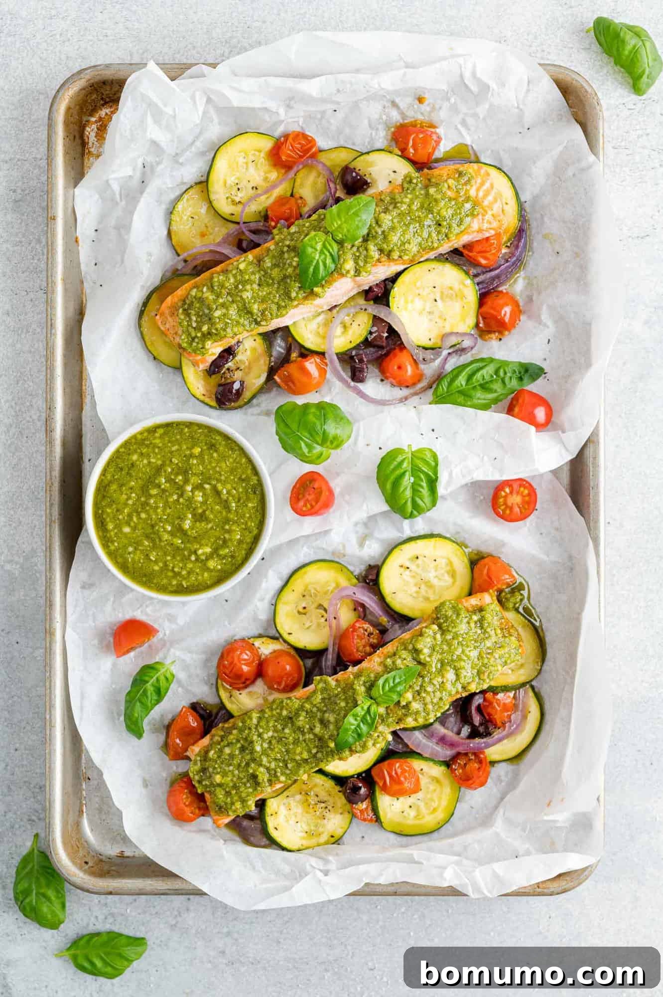 Overhead view of two open packets of pesto salmon with perfectly cooked vegetables, ready to be enjoyed.