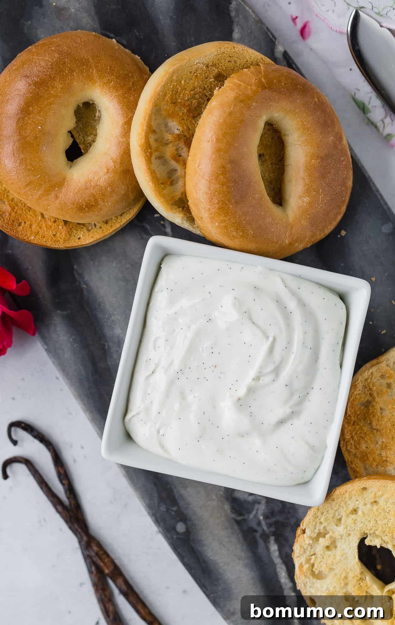 Cream cheese with vanilla beans, surrounded by bagels, showcasing key ingredients.