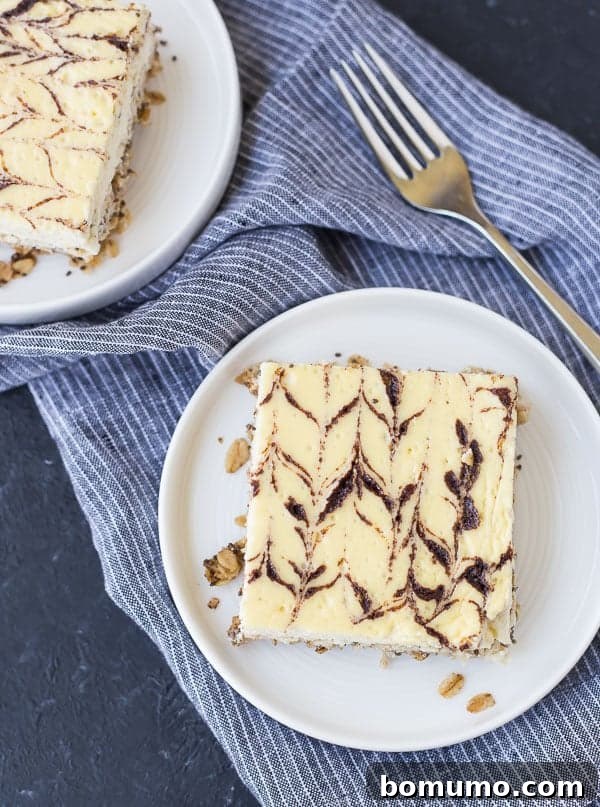 Overhead shot of a single serving of breakfast cheesecake on a white plate, accompanied by a fork. The cake reveals its creamy texture and oat crust, with a prominent cinnamon swirl on top.