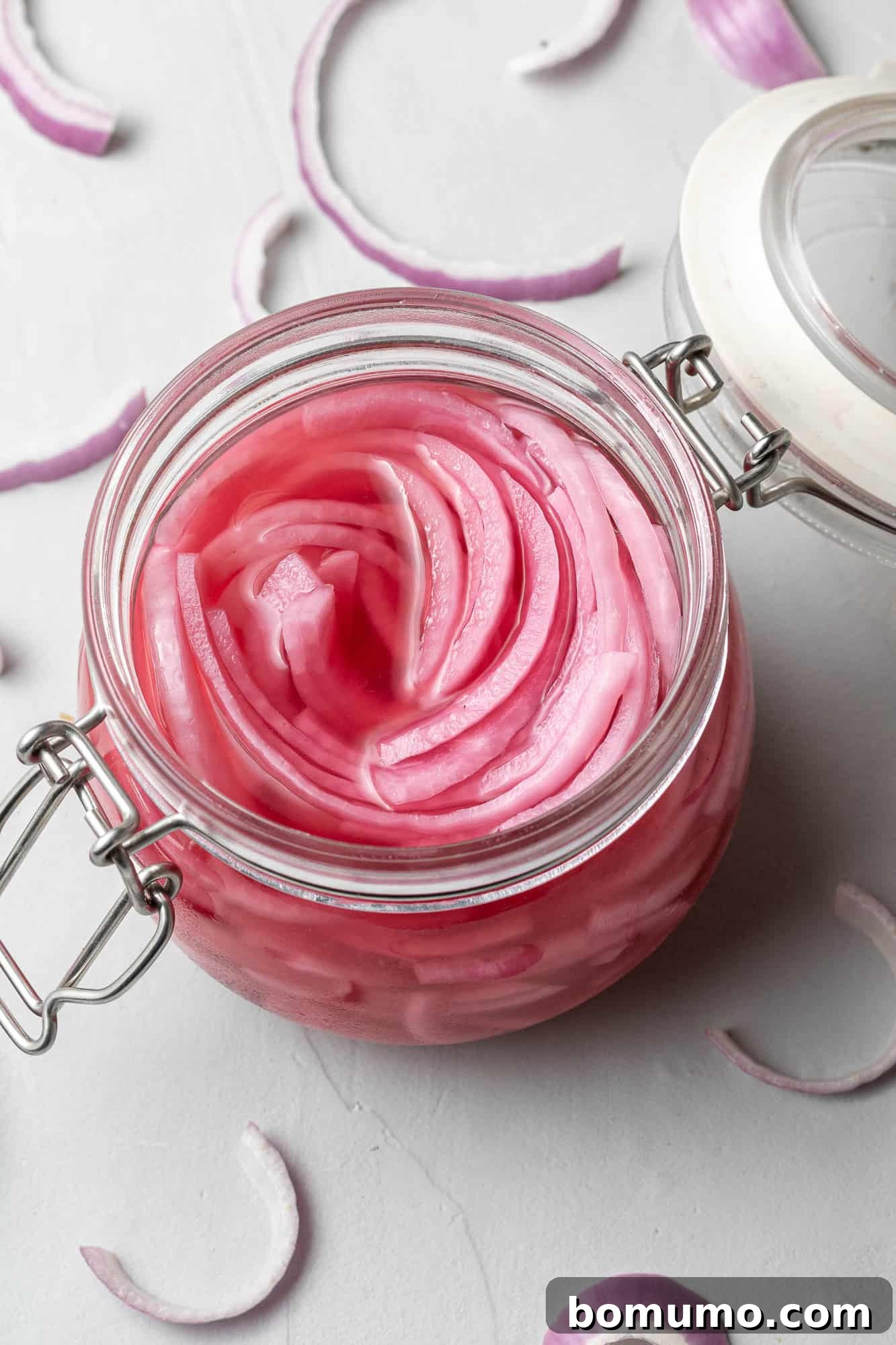 Close-up of vibrant sliced pickled red onions neatly packed in a clear glass jar.