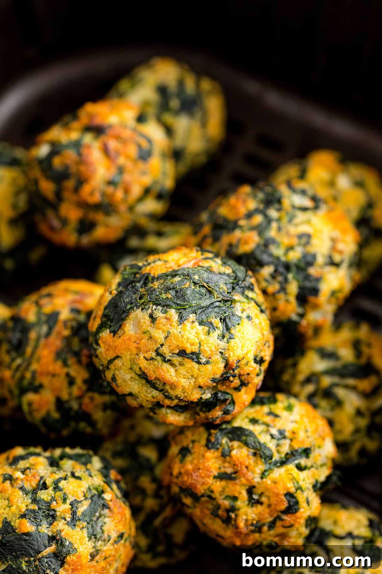 Close up of assorted cooked spinach balls inside the air fryer.