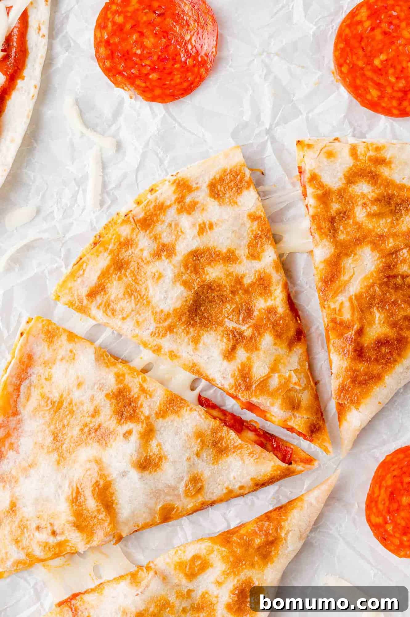 Pizza-Dilla Melt 2 A golden-brown pizza quesadilla, expertly cut into four delicious wedges, showcasing its melty cheese and pepperoni filling.