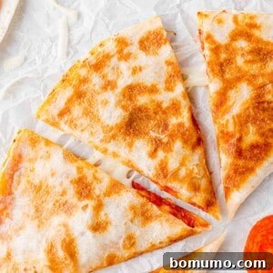 Overhead view of a perfectly cooked pizza quesadilla, cut into wedges, showing melted cheese and pepperoni.