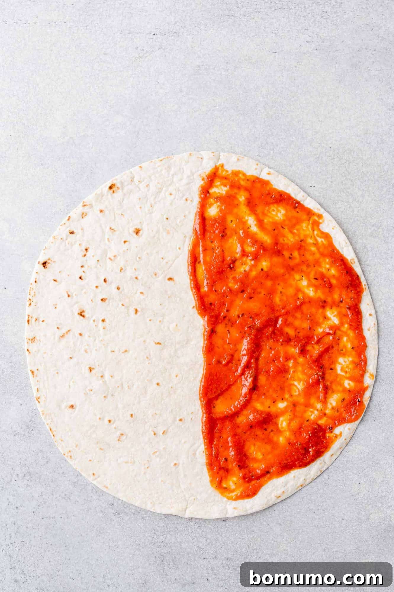 Pizza-Dilla Melt 5 Pizza sauce spread on half of a tortilla, ready for cheese and pepperoni.
