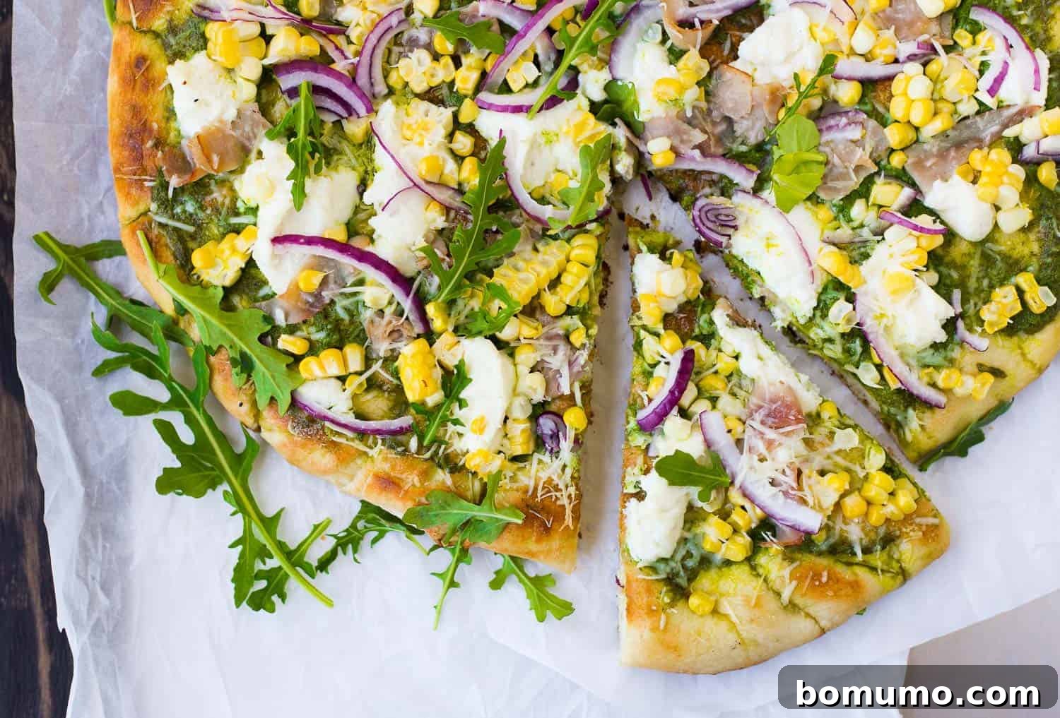 A delectable slice of grilled pizza being pulled away from a round, golden-crusted pizza, highlighting the melted cheese and fresh toppings.